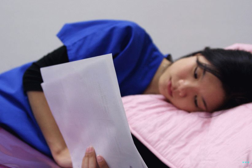 L'immagine mostra una persona che legge documenti mentre è sdraiata.